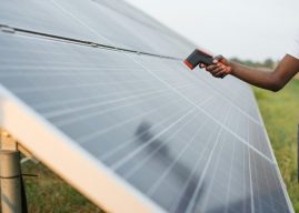 Man checking heat of solar panels with thermal imager