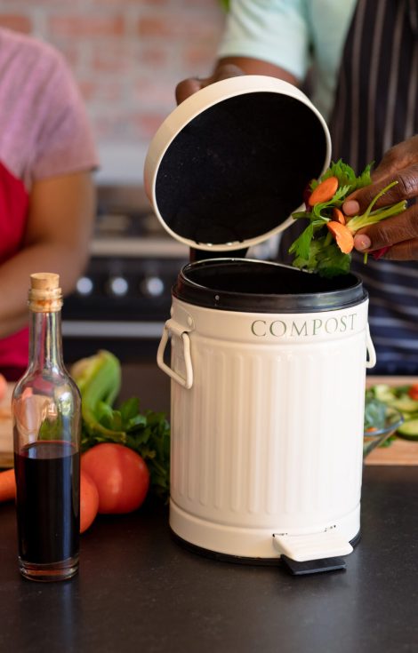 Midsection of african american senior couple cooking together in kitchen using compost bin. retirement lifestyle, leisure and spending time at home.