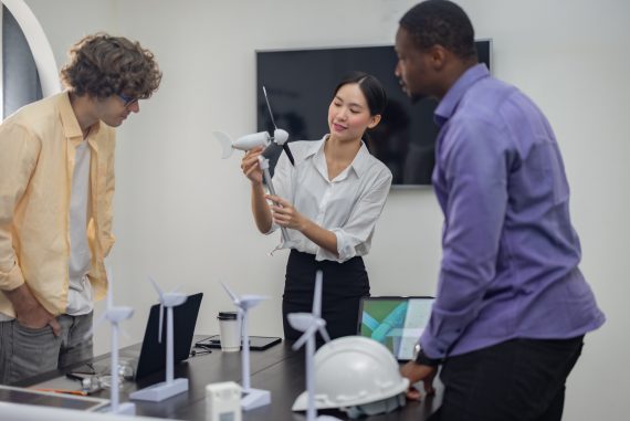 A diverse startup team develop, collaborates on a powerful, lightweight, portable wind turbine prototype, aligning with potential user demand and renewable energy needs to secure investor funding.
